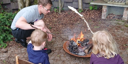 Familie bager snobrød over bålfad