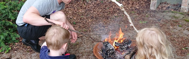 Familie bager snobrød over bålfad