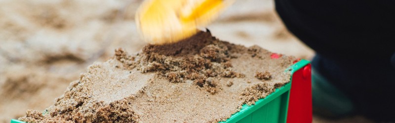 Barn fylder sand i traktorvogn