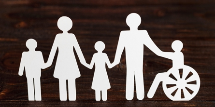 Billedet viser 5 personer som holder hinanden i hånden, hvoraf en i kørestol. Billedet illustrerer sammenhold.