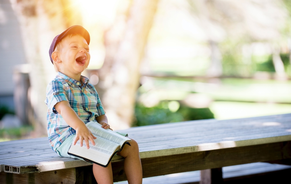 Boy laughing with a book on his knees