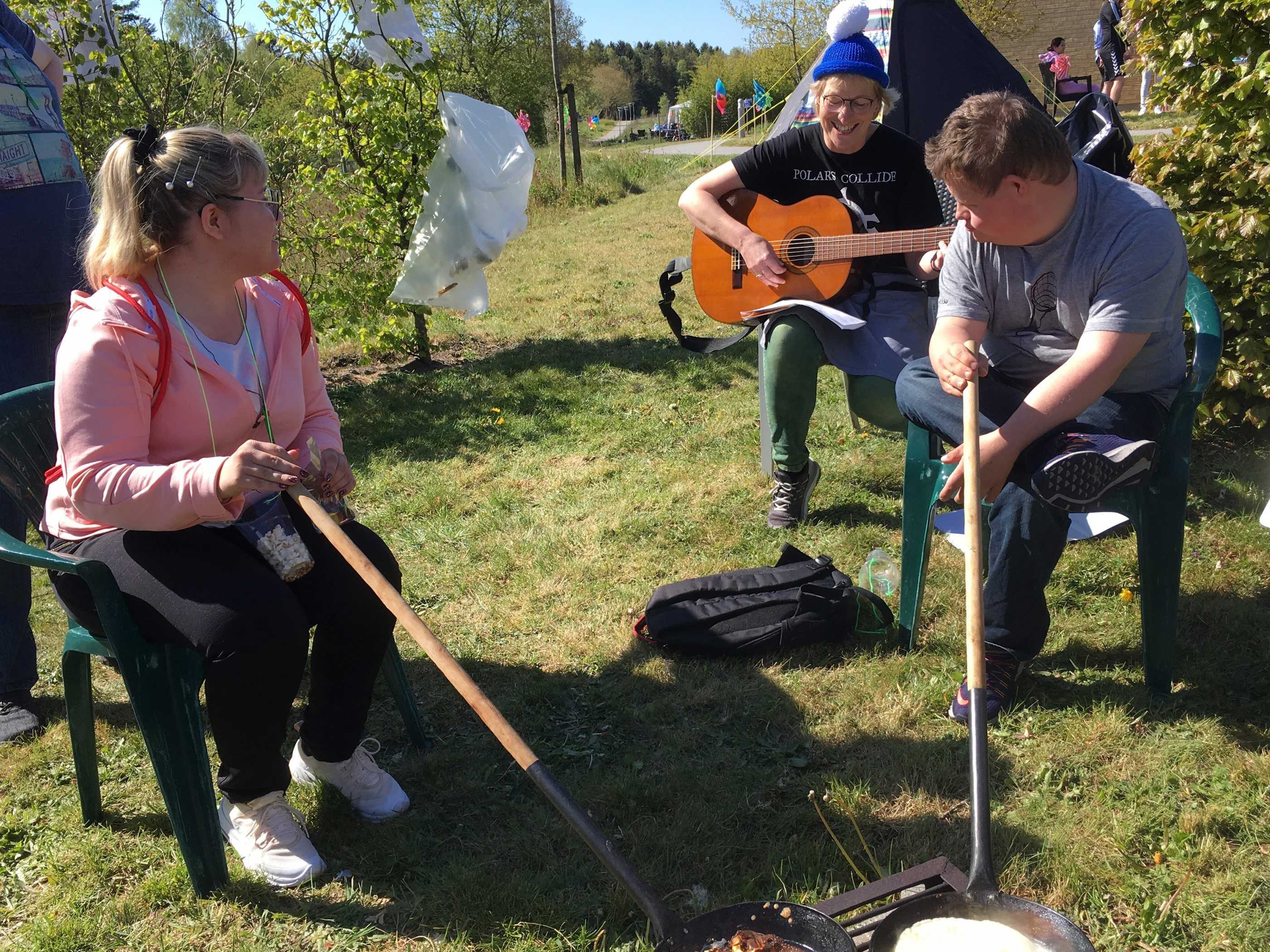 Personer i gang med at lave snobrød over bål