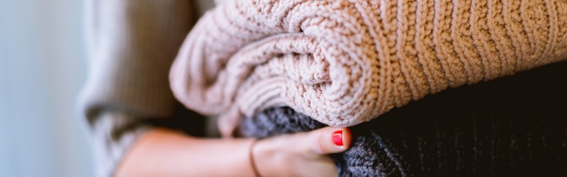 Kvinde går med en bunke foldet tøj