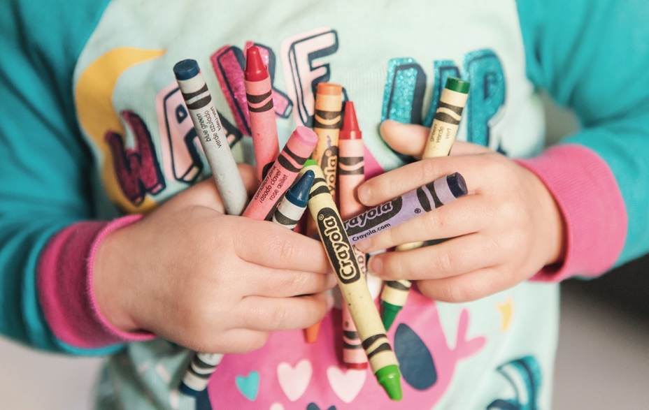 Close-up of child holding crayons