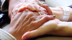 En ældre person holder en anden person i hånden for at skildre omsorg